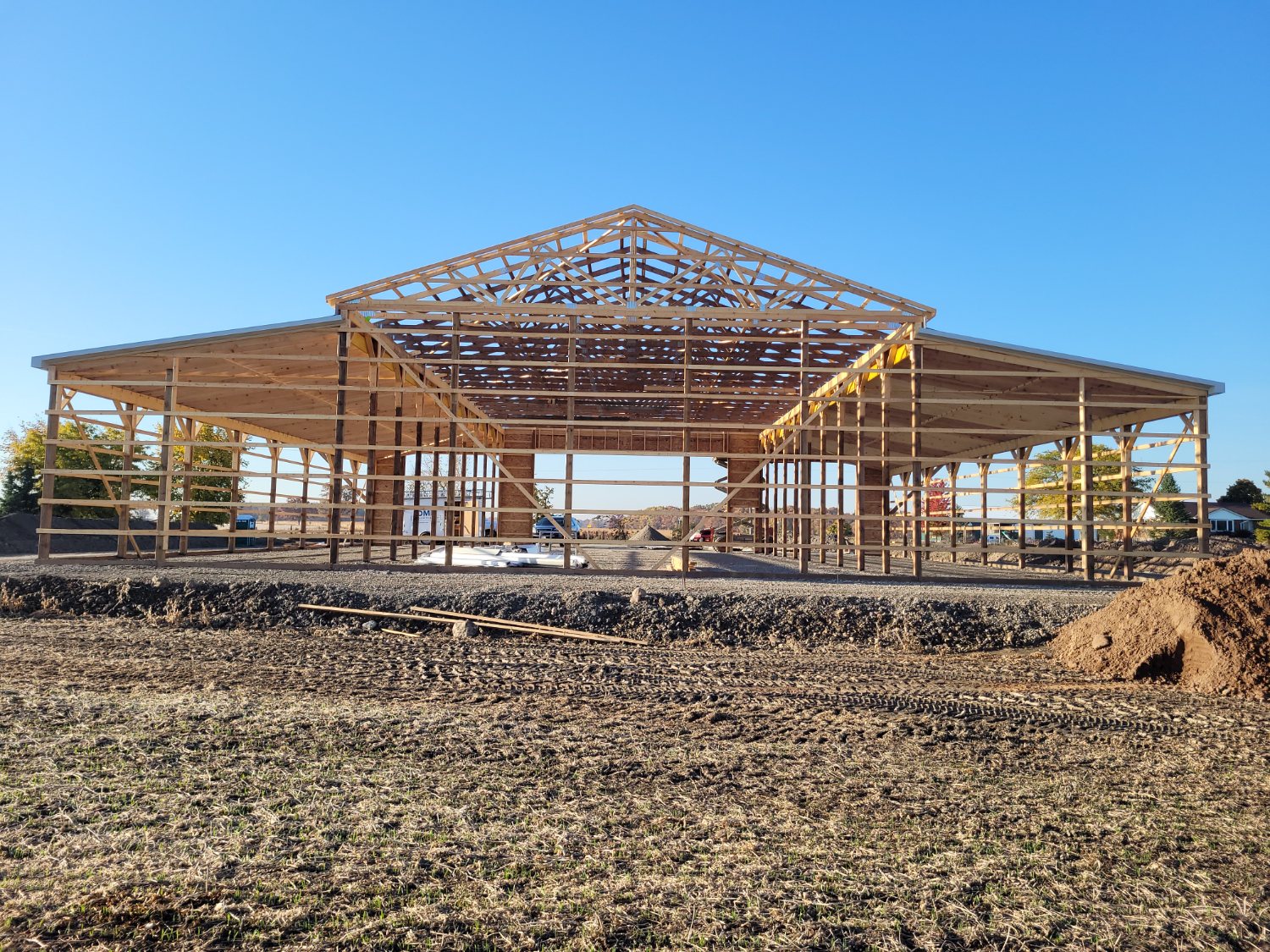 Large post-frame building under construction with engineered wood trusses